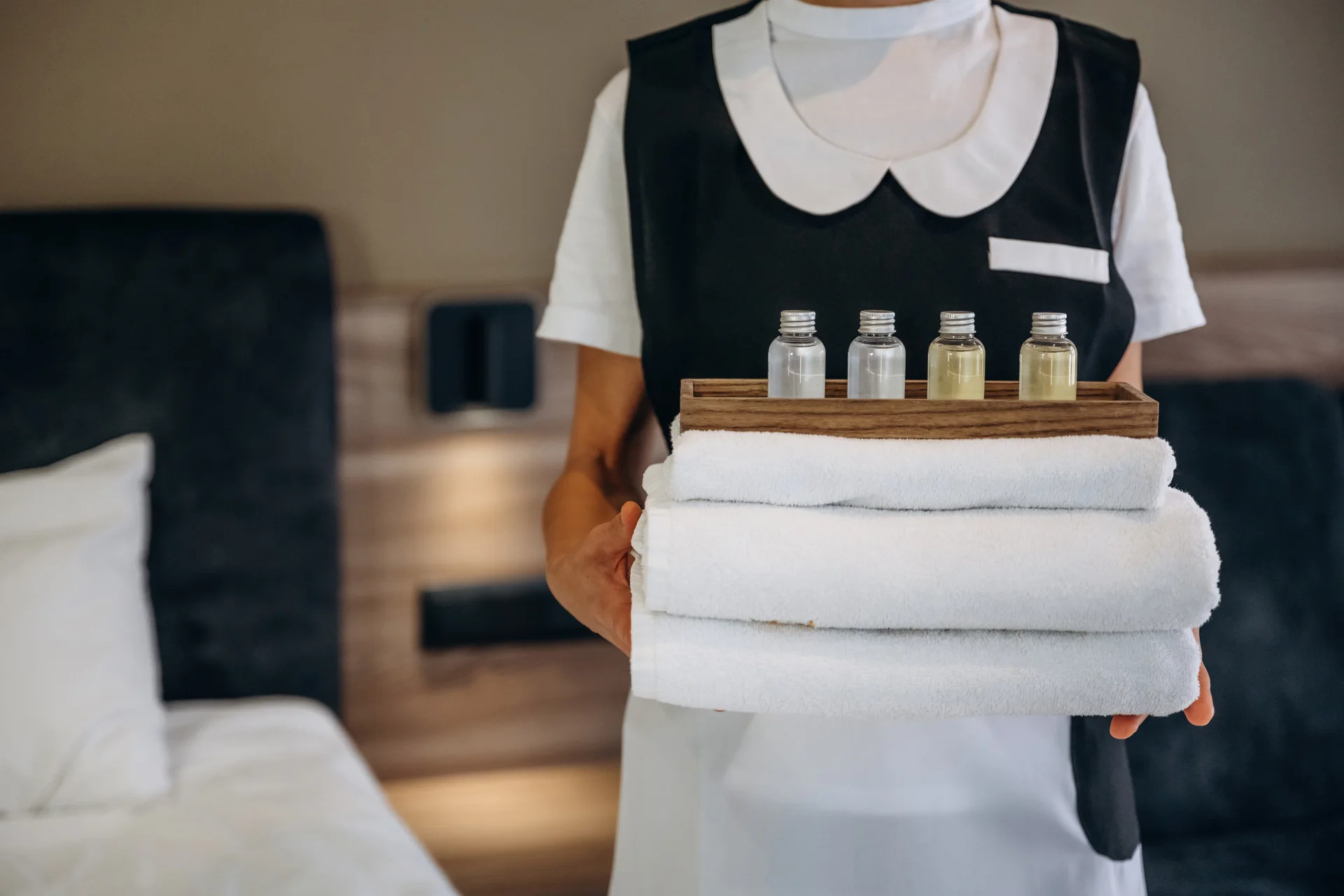 An attendant holding towels and four small toiletry bottles