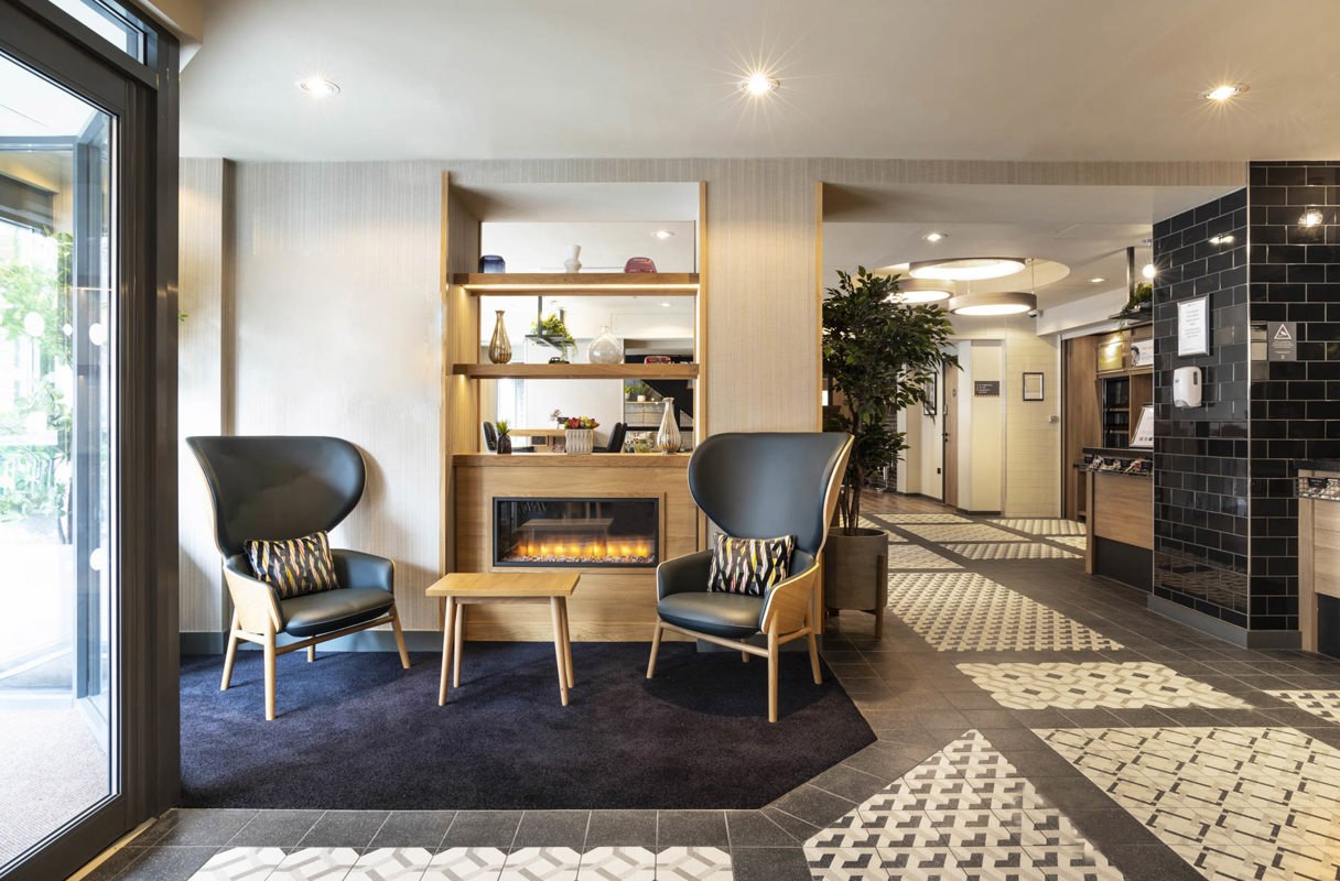 Detail of seating area with armchairs next to a fireplace at Point A Hotel Paddington